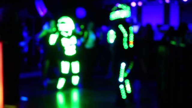 Out of Focus Dancers Wearing LED Light Suits at Disco Dance Party