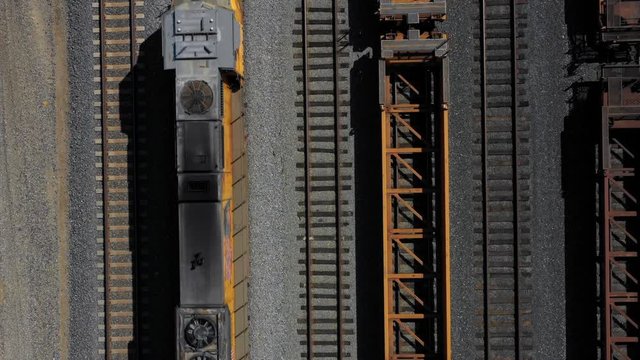 Looking down at multiple rows of train tracks as a locomotive passes by.