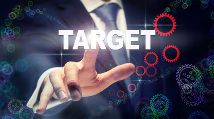 A businessman pressing a Target business concept on a graphical display of cogs