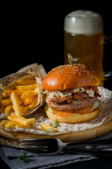 Appetizing Burger on a dark background with beer in the background
