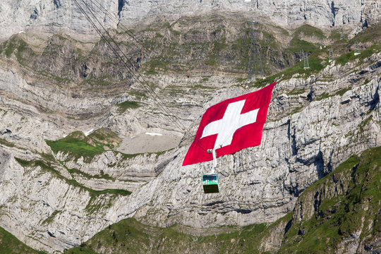 Schwaegalp, Switzerland: 31.07.2018 - Huge Swiss national flag (80mx80m, 700 kg), which is the biggest Swiss flag in the world) hangs on the Saentis mountain on National Day