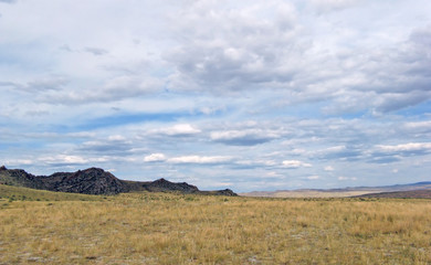 Wide steppe with yellow grass under a blue sky with white clouds Sayan mountains Siberia Russia