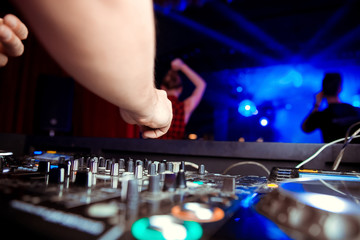 club DJ in headphones with sound mixer in nightclub