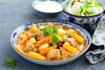 Beef stew with tomato sauce in a pan on wooden background. azu.