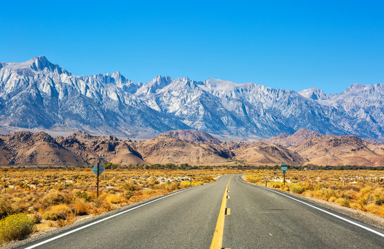 Empty Road Near Lone Pine With Rocks Of The Alabama Hills And The Sierra Nevada In The Background, Inyo County, California, United States.