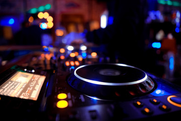 Fototapeta na wymiar DJ behind the decks in a nightclub. DJ spinning plate. people dancing in a nightclub. disco
