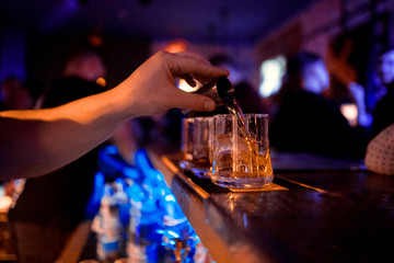 barman at work, pouring spirit into a glass. concept about professions and drinks