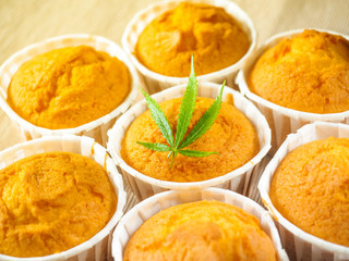 Delicious homemade baked cinnamon muffins with marijuana leaf garnish. Cookies with cannabis and buds. Treatment of medical marijuana for use in food.