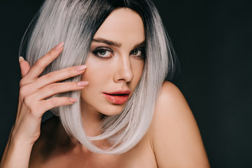 fashionable naked woman posing in grey wig and showing nails with manicure, isolated on black