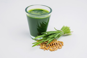 Shot glass of wheat grass with fresh cut wheat grass and wheat grains