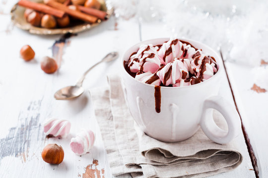 Hot chocolate with marshmallow candies in white rustic ceramic cup on old light vintage wooden background. Selective focus.