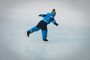 little boy skating on ice in winter