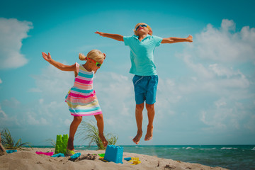 happy little boy and girl play jump on beach