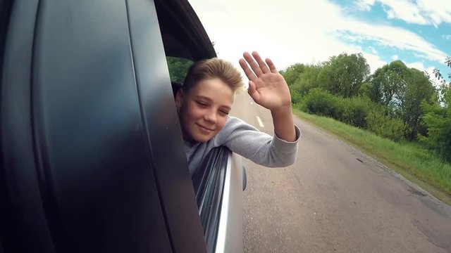 Good mood. Happy joyful teen boy rides travels on road in the car . Summer romantic adventures and trips, childhood memories and dreams. Headwind blowing in face. Slow motion