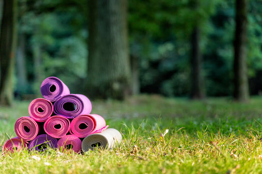 joga matts stacked on the green grass, springtime in public park