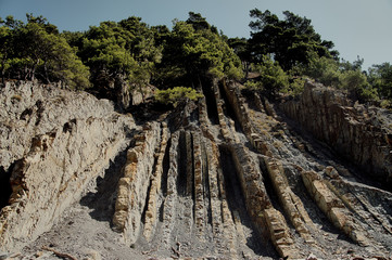 Steep cliffs with vertical and horizontal sedimentary layers of the ancient sea against a blue sky....