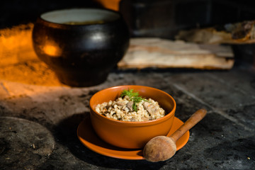 Ukrainian porridge in a clay bowl on the background of the oven