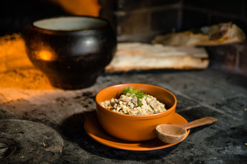 Ukrainian porridge in a clay bowl on the background of the oven