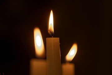 Three candle flames with a dark background