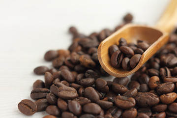 mountain of coffee beans with a wooden spatula front view close-up / natural roasted selected