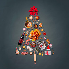 Christmas tree made with various Christmas food: turkey on platter, roasted ham, sweets and...