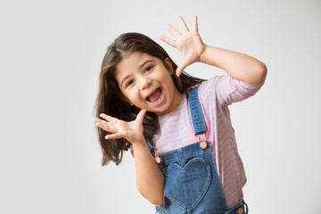 Adorable preschooler girl showing palms and funny grimace. Cute joyful Hispanic child having fun....