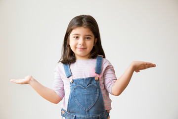 Cheerful Latin kid with shrug gesture asking something and looking at camera. Portrait of little...