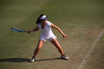 天然芝のコートでフォアハンドストロークを打つジュニアテニスプレイヤー