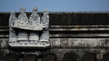 Figurines showing four holy and historically dressed men as roof top decoration in an old town in China, Asia