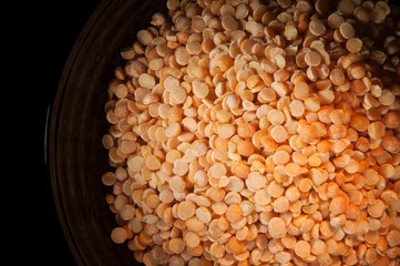 Close up of yellow split peas in a black bowl from above