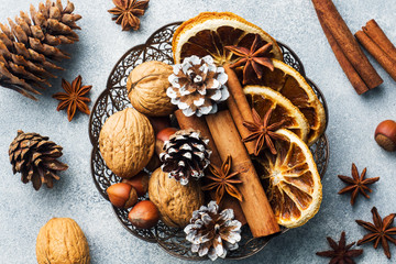 Winter food ingredients nuts cones oranges cinnamon star anise in a bowl. Rustic style.