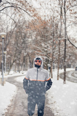 Fototapeta na wymiar Man jogging in a cold winter snowy day outdoors.