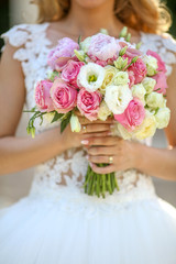 Obraz na płótnie Canvas Hands of beautiful bride holding bouquet of flowers