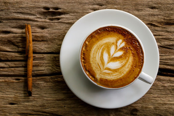 Hot cofffee cup on wooden with painting leaf