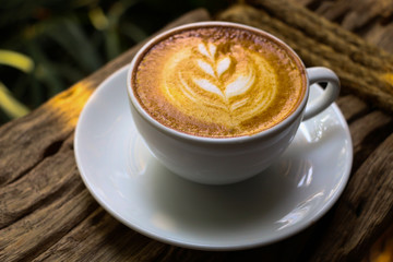Hot cofffee cup on wooden with painting leaf