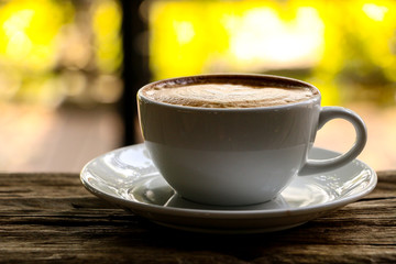 Hot cofffee cup on wooden with painting leaf