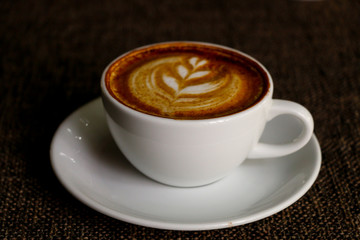 Hot cofffee cup on wooden with painting leaf
