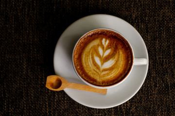 Hot cofffee cup on wooden with painting leaf