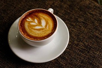 Hot cofffee cup on wooden with painting leaf