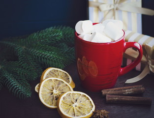 Red cup of coffee or hot chocolate with marshmallow on wooden dark background. Cinnamon sticks, stars with bokeh. Winter concept. Hot coffe with marshmallow.