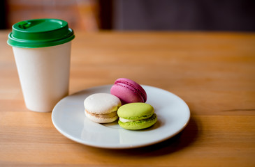 Colorful macarons and a paper coffee cup to go in the cafe