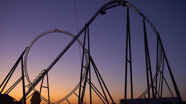Silhouette of roller coaster against sunset sky