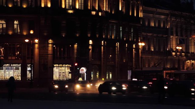 Foggy footage of street traffic and street facades of the night city. Beautiful dark urban background. Winter scene, street lights and headlights of moving cars. Europe, Russia, Saint Petersburg, Blur