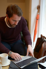 Young man working on his laptop from coffee shop - obrazy, fototapety, plakaty
