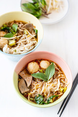 Spicy rice noodles soup in a bowl with chopsticks and fresh vegetables, Asian food