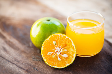 Green tangerine orange fruit and juice on wooden table