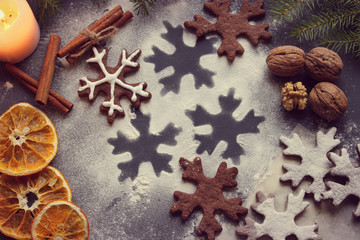 Postcard Christmas cookies in the form of flakes, decorated with dried orange, cinnamon sticks and anise, the background is sprinkled with flour. Copy space.Tinted effect.