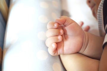 Close-up hands of baby 5 mounts sleeping on the bed.