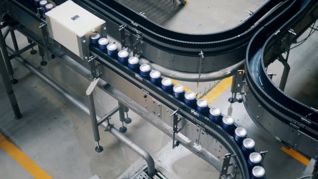 Aluminum cans moving on a conveyor in a row, top view.