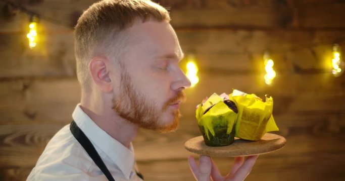 Cute young bearded male waiter working in a bakery